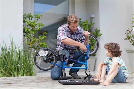 family on bikes - Father helping son fix bicycle Stock Photo - Premium Royalty-Free, Code: 649-05657232