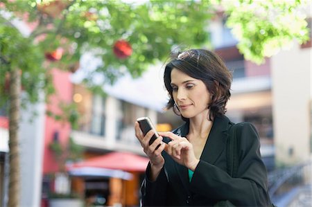 sending - Businesswoman using cell phone outdoors Stock Photo - Premium Royalty-Free, Code: 649-05657423