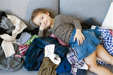 Smiling girl laying on pile of laundry Stock Photo - Premium Royalty-Free, Code: 649-05801039