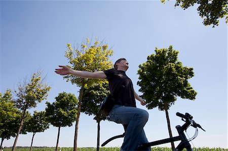 Man riding bicycle with no hands Stock Photo - Premium Royalty-Free, Code: 649-05801062