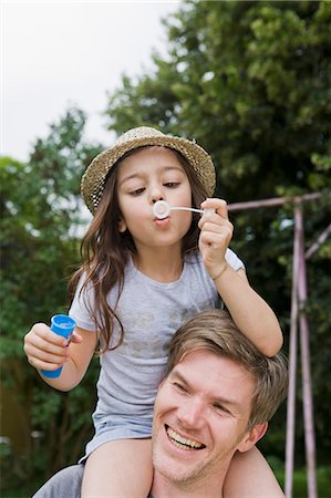 Girl with bubbles on fathers shoulders Stock Photo - Premium Royalty-Free, Code: 649-05801122