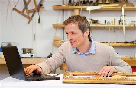 Carpenter working on laptop in shop Stock Photo - Premium Royalty-Free, Code: 649-05801737