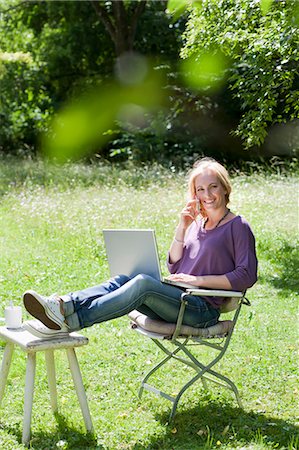 simsearch:649-05819818,k - Smiling woman using laptop outdoors Foto de stock - Sin royalties Premium, Código: 649-05819806