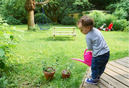 Toddler boy watering plants in backyard Stock Photo - Premium Royalty-Free, Code: 649-05820010