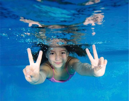 peace sign - Smiling girl playing in swimming pool Stock Photo - Premium Royalty-Free, Code: 649-05820625