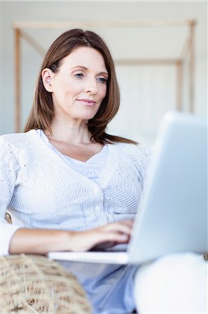 Woman using laptop in armchair Stock Photo - Premium Royalty-Free, Code: 649-05949920