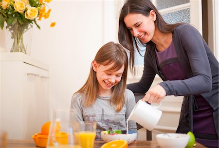 Woman pouring milk for daughter at table Stock Photo - Premium Royalty-Free, Code: 649-05950568