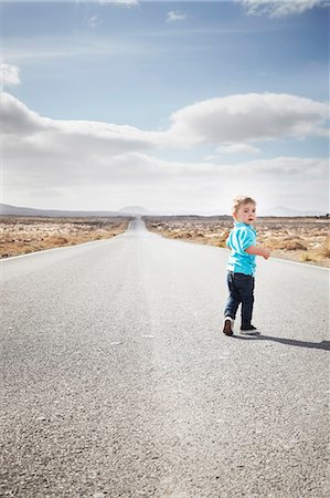 future of the desert - Boy walking on paved rural road Stock Photo - Premium Royalty-Free, Code: 649-05950797