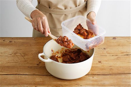 Woman spooning meat into tupperware Stock Photo - Premium Royalty-Free, Code: 649-06000563