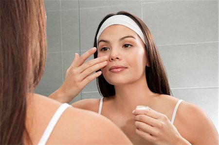 Woman examining her face in mirror Stock Photo - Premium Royalty-Free, Code: 649-06000643