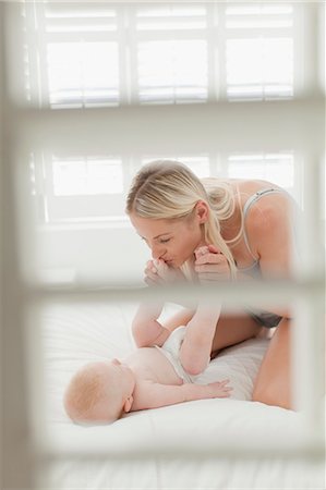 daughter kissing mother - Mother kissing babys feet on bed Stock Photo - Premium Royalty-Free, Code: 649-06001121