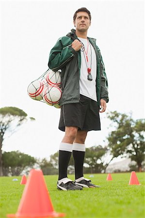 Coach carrying soccer balls on pitch Stock Photo - Premium Royalty-Free, Code: 649-06040284
