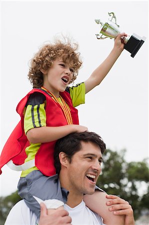 Coach carrying child with trophy Stock Photo - Premium Royalty-Free, Code: 649-06040327