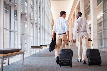 Businessmen rolling luggage in hallway Stock Photo - Premium Royalty-Free, Code: 649-06040649