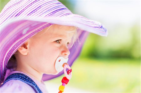 sunhat - Toddler girl sucking pacifier outdoors Stock Photo - Premium Royalty-Free, Code: 649-06112817