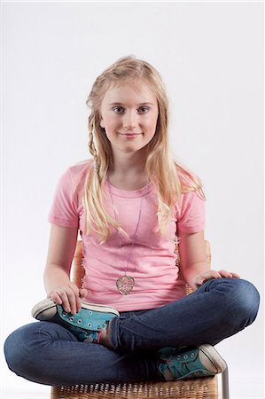 Smiling girl sitting cross legged Stock Photo - Premium Royalty-Free, Code: 649-06113076