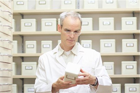 Pharmacist examining box of pills Stock Photo - Premium Royalty-Free, Code: 649-06165162