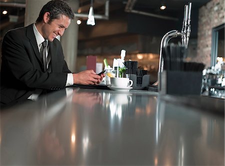 restaurant counter - Businessman using cell phone in cafe Stock Photo - Premium Royalty-Free, Code: 649-06165224