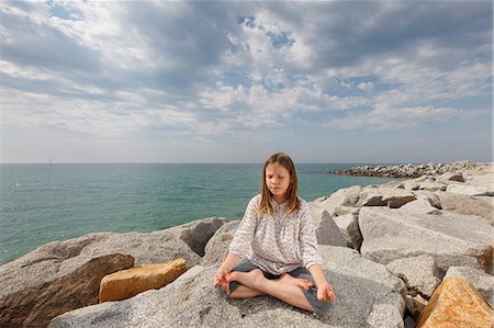 Girl meditating on rocks at beach Stock Photo - Premium Royalty-Free, Code: 649-06305496