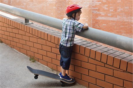 skateboarding - Boy peering over balcony outdoors Stock Photo - Premium Royalty-Free, Code: 649-06305506