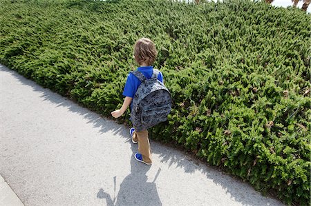 Boy walking by shrubs outdoors Stock Photo - Premium Royalty-Free, Code: 649-06305508