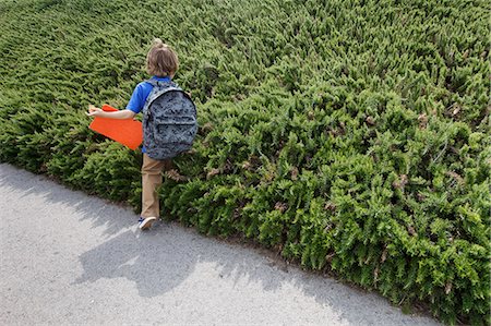 Boy walking by shrubs outdoors Stock Photo - Premium Royalty-Free, Code: 649-06305509