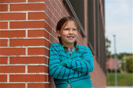 single brick - Smiling girl leaning against brick wall Stock Photo - Premium Royalty-Free, Code: 649-06305523