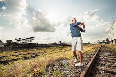 Man playing golf on train tracks Stock Photo - Premium Royalty-Free, Code: 649-06305709