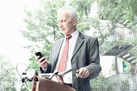 Businessman using cell phone on bicycle Stock Photo - Premium Royalty-Free, Code: 649-06305874