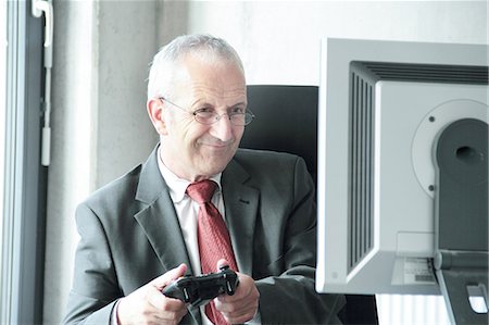 Businessman playing video games at desk Foto de stock - Sin royalties Premium, Código: 649-06305878