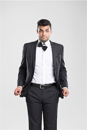 Man in tuxedo pulling at empty pockets Stock Photo - Premium Royalty-Free, Code: 649-06353190