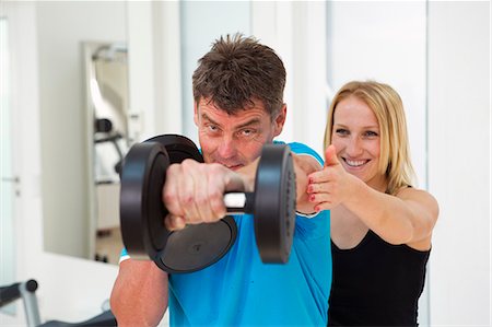 exercising with friend - Trainer adjusting man's form in gym Stock Photo - Premium Royalty-Free, Code: 649-06400823