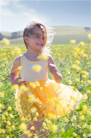 Jeune fille souriante, jouant dans le champ de fleurs Photographie de stock - Premium Libres de Droits, Code: 649-06432408