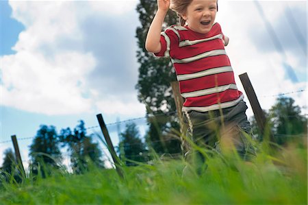 Boy playing in grassy field Stock Photo - Premium Royalty-Free, Code: 649-06432504