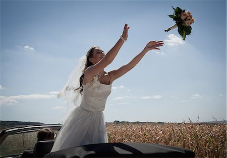 smiling bride - Newlywed bride tossing bouquet from car Stock Photo - Premium Royalty-Free, Code: 649-06432543