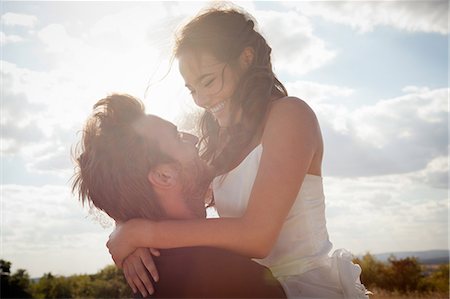 Newlywed groom holding bride outdoors Stock Photo - Premium Royalty-Free, Code: 649-06432563