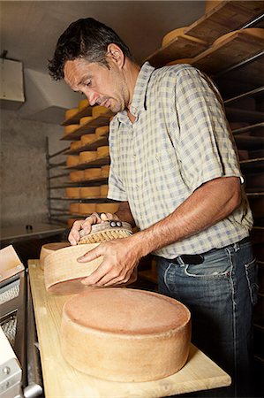 Worker finishing wheel of cheese in shop Stock Photo - Premium Royalty-Free, Code: 649-06433422