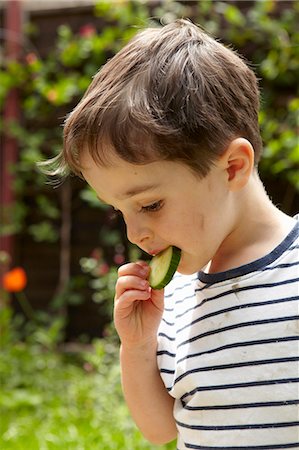 Boy eating cucumber outdoors Stock Photo - Premium Royalty-Free, Code: 649-06488916