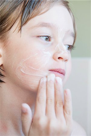 Girl rubbing moisturizer on her face Stock Photo - Premium Royalty-Free, Code: 649-06489053