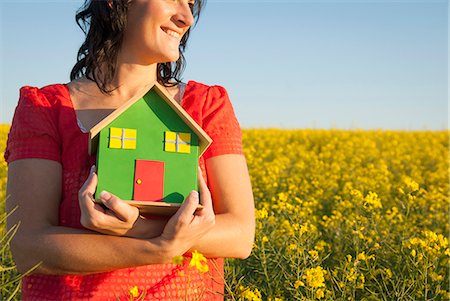 Woman holding model house in field Stock Photo - Premium Royalty-Free, Code: 649-06489089