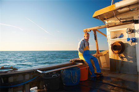 fisherman (male) - Fisherman sitting on ledge of boat Stock Photo - Premium Royalty-Free, Code: 649-06489853