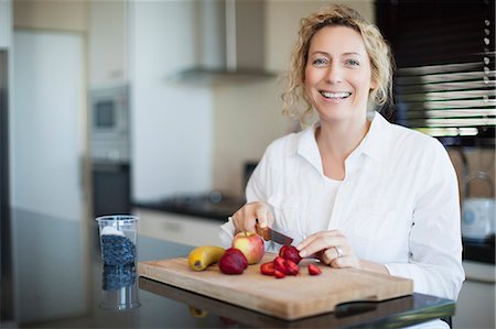 single strawberry - Woman cutting fruit in kitchen Stock Photo - Premium Royalty-Free, Code: 649-06532811