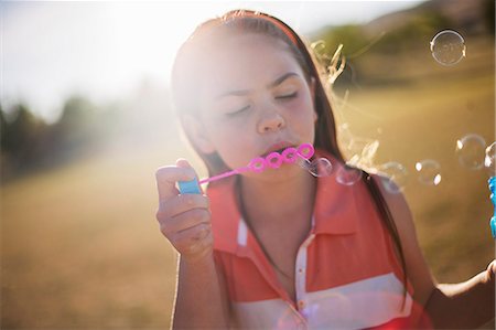 Girl blowing bubbles outdoors Stock Photo - Premium Royalty-Free, Code: 649-06622472