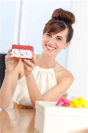 Woman holding present at table Stock Photo - Premium Royalty-Free, Code: 649-06622566