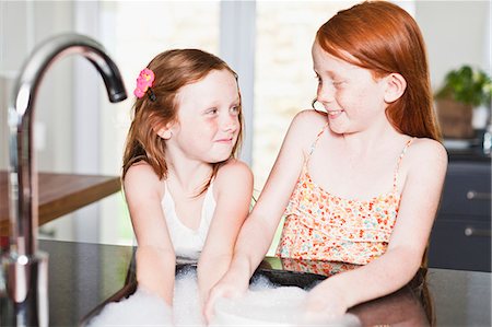 red hair children - Smiling girls washing dishes in sink Stock Photo - Premium Royalty-Free, Code: 649-06716983