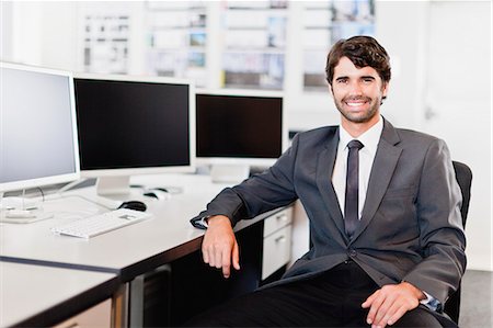 suit pose - Businessman smiling at desk Stock Photo - Premium Royalty-Free, Code: 649-06717051
