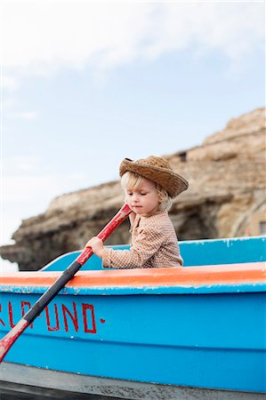 side view of person rowing in boat - Toddler girl rowing boat on beach Stock Photo - Premium Royalty-Free, Code: 649-06717332