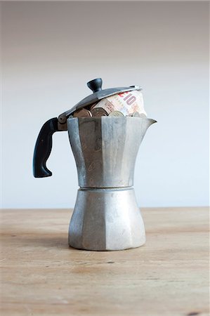 Coffee pot full of money on desk Stock Photo - Premium Royalty-Free, Code: 649-06717474