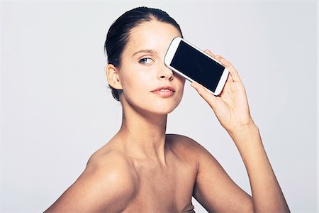 eyes looking away - Woman holding cell phone by face Stock Photo - Premium Royalty-Free, Code: 649-06717542