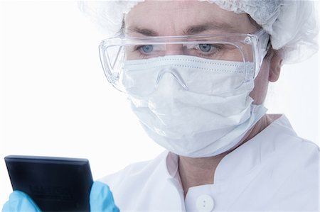 surgical mask - Doctor in face mask using tablet computer Stock Photo - Premium Royalty-Free, Code: 649-06717872